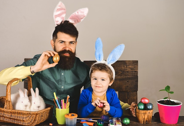 Familia feliz padre e hijo pintando huevos para vacaciones de pascua niño lindo niño y hombre barbudo en