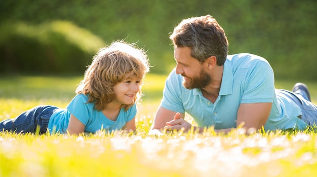 La familia feliz de padre e hijo se relaja en el parque de verano amistad de hierba verde