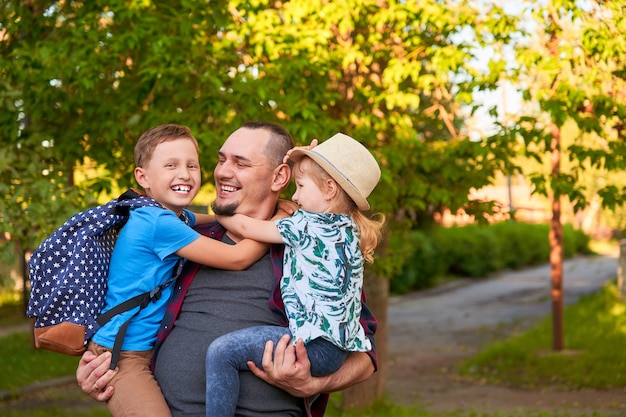 Familia feliz de padre e hijos. El padre sostiene a los niños en sus brazos