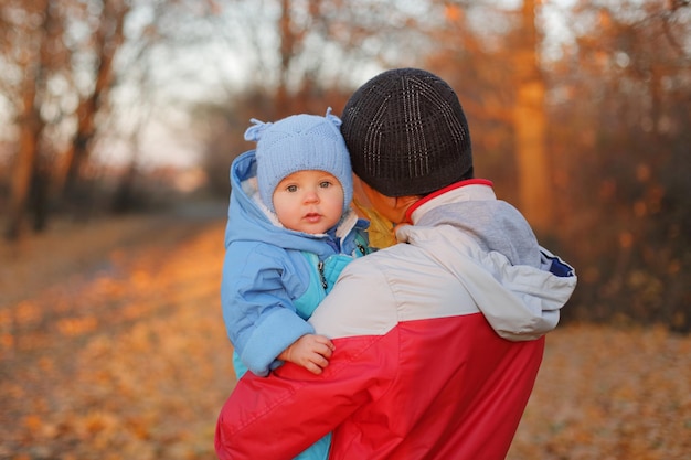 Foto familia feliz padre y hija hija jugando y en el parque de otoño hombre posando hacia atrás sosteniendo a la niña entre hojas de colores