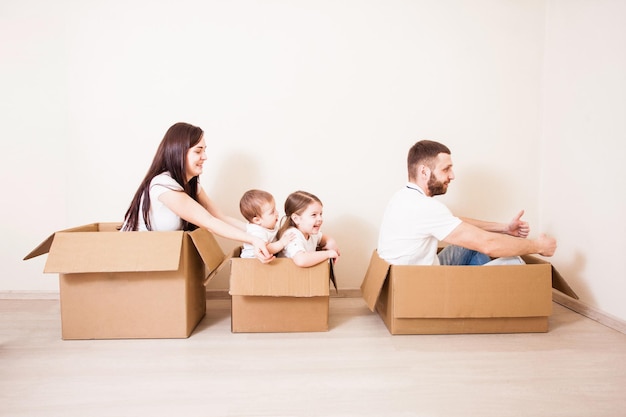 Familia feliz. Padre, madre y dos hijos divirtiéndose juntos. Día de la mudanza y concepto de entrega urgente