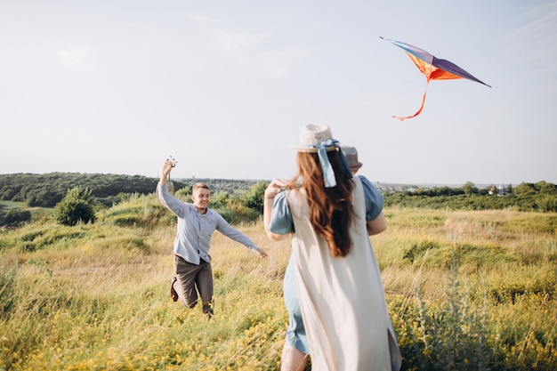 Familia feliz padre de madre e hijo hijo lanzar una cometa en la naturaleza al atardecer