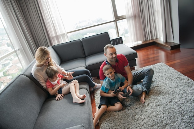 Familia feliz. Padre, madre e hijos jugando videojuegos Padre e hijo jugando videojuegos juntos en el suelo