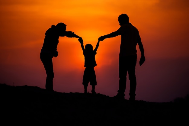 Familia feliz, padre, madre, hijo en la naturaleza, puesta de sol