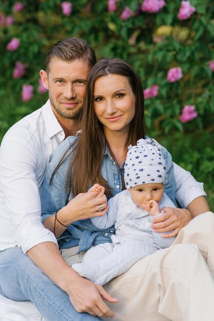 Una familia feliz con padres jóvenes del milenio y un hijo pequeño sentados en una manta de picnic y divirtiéndose juntos es un concepto familiar de estilo de vida al aire libre