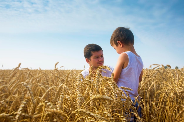 Família feliz Pai e filho no campo de trigo Macho mostra a espiga de trigo do menino