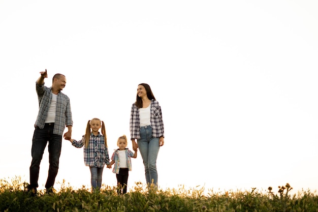 Família feliz pai mãe e filhas caminham na natureza no campo no verão ao pôr do sol Pais com filhos passam tempo juntos no fim de semana Família feliz e conceito de infância