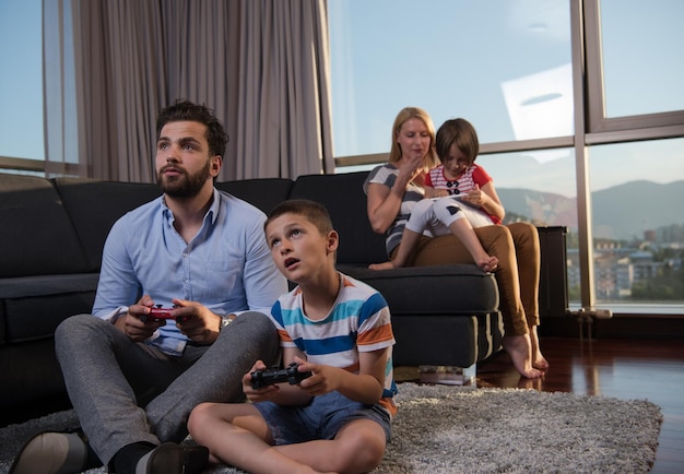 Família feliz. Pai, mãe e filhos jogando videogame Pai e filho jogando videogame juntos no chão