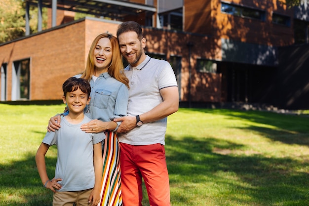 Família feliz. Pais amorosos e satisfeitos, sorrindo e ao lado do filho