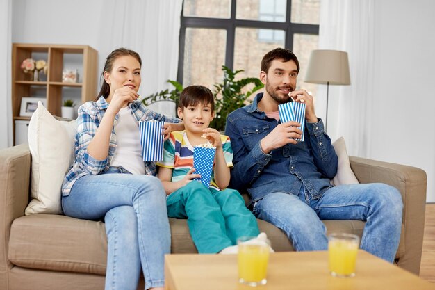 Foto familia feliz con palomitas de maíz viendo la televisión en casa