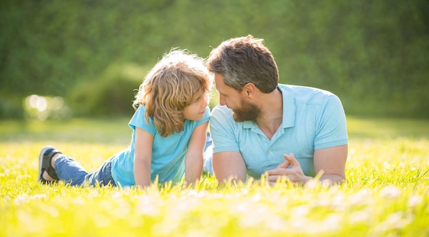 La familia feliz de papá e hijo se relaja en el parque de verano adopción de hierba verde