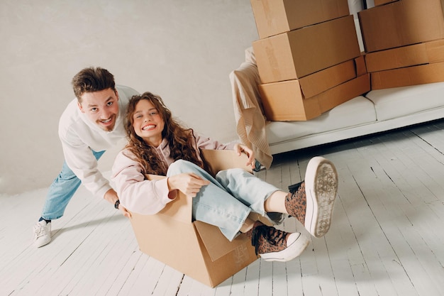 Familia feliz pareja joven hombre transportar trasladar mujer dentro de la caja mudarse con cajas de cartón a un nuevo concepto de apartamento en casa