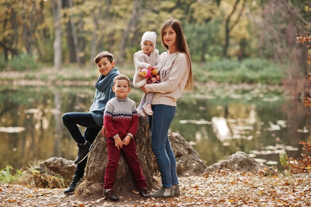 Familia feliz en el parque de hojas de otoño. Madre con tres hijos.