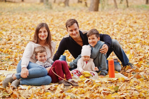 Familia feliz en el parque de hojas de otoño. Tres niños.