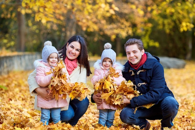 Familia feliz en el parque otoño. Madre, padre y dos hijas en plena naturaleza.