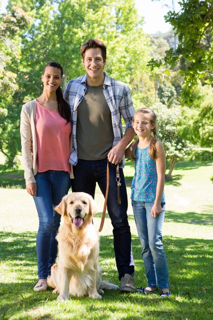 Familia feliz paseando a su perro en el parque