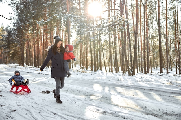 Familia feliz en un paseo al aire libre en el bosque soleado de invierno