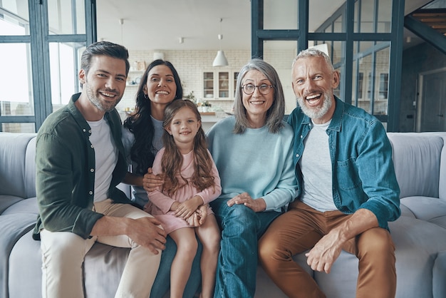 Família feliz, passando um tempo juntos e sorrindo enquanto estão sentados no sofá em casa