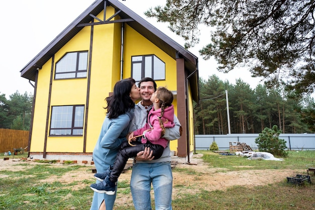 Foto familia feliz en el patio de una casa inacabada - compra de una cabaña préstamo hipotecario reubicación persona persona de construcción