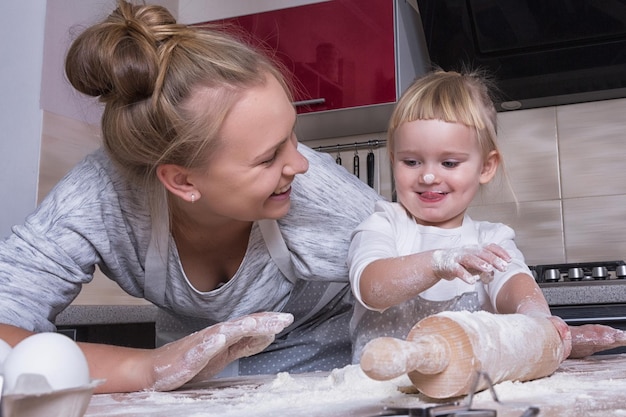 Familia feliz Una pequeña hija pasa tiempo con su madre en la cocina para hornear galletas Día de la Madre