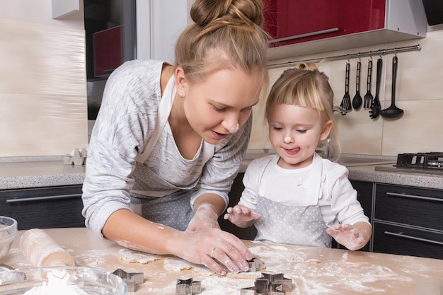 Familia feliz Una pequeña hija pasa tiempo con su madre en la cocina