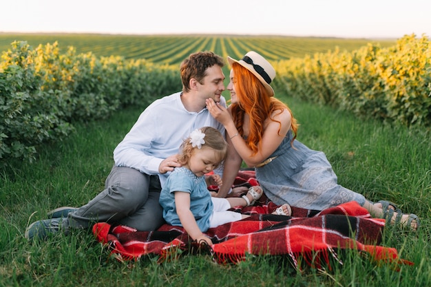 Familia feliz con pequeña hija pasar tiempo juntos en el campo soleado