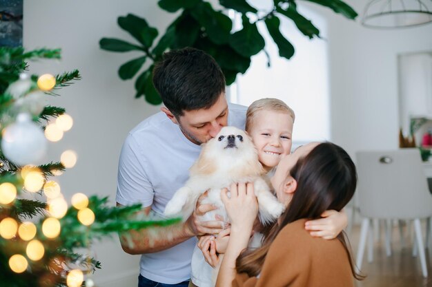 Familia feliz con perro cerca del árbol de Navidad