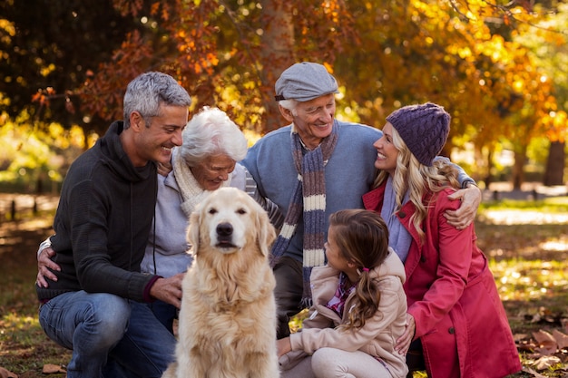 Familia feliz con perro en el parque durante el otoño