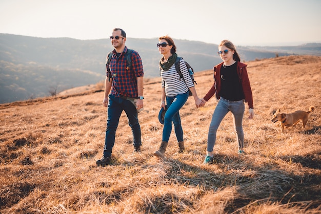 Familia feliz con perro senderismo en una montaña