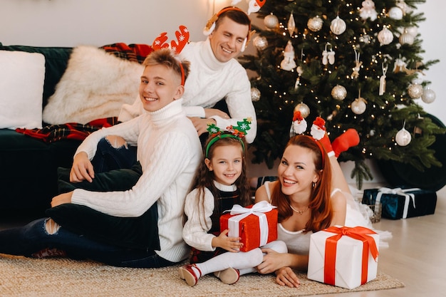 Família feliz perto da árvore de natal com presentes.