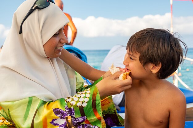 Familia feliz en un picnic cerca del mar y la madre alimentando a su hijo