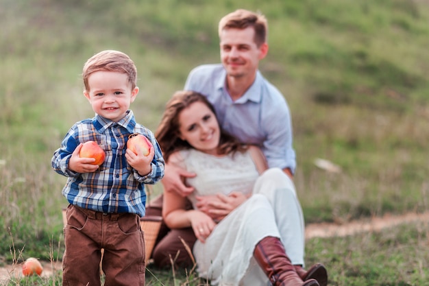 Familia feliz en un picnic. niño pequeño con manzanas en primer plano