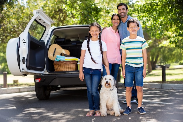 Familia feliz en un picnic de pie junto a su automóvil