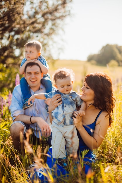 Foto familia feliz plantea en el campo en un clima soleado