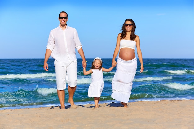 Familia feliz en la playa caminando de arena