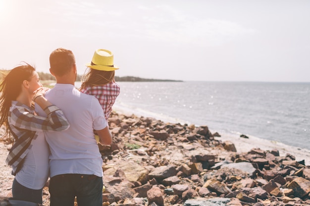 Familia feliz en la playa Gente divirtiéndose en las vacaciones de verano. Padre, madre e hijo contra el azul del mar y el cielo. Viajes de vacaciones.