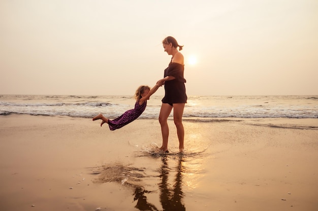 Familia feliz en la playa. madre abrazando a su hija y volando turismo con niños