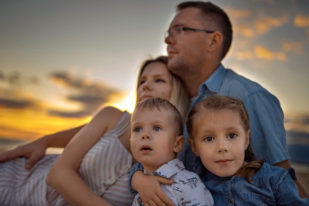 Familia feliz en la playa sentada en la arena al atardecer