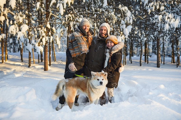 Família feliz posando com cachorro no inverno