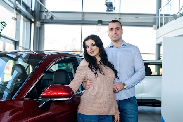 Família feliz posando com carro no showroom