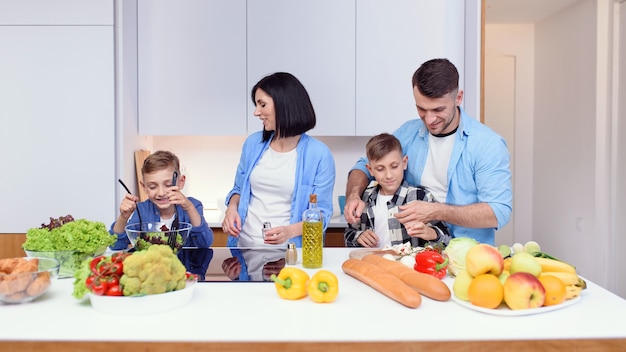 Familia feliz preparando un desayuno vegetariano saludable con verduras y en la cocina