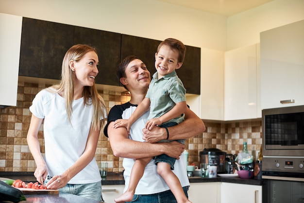 Família feliz preparando legumes juntos em casa na cozinha.