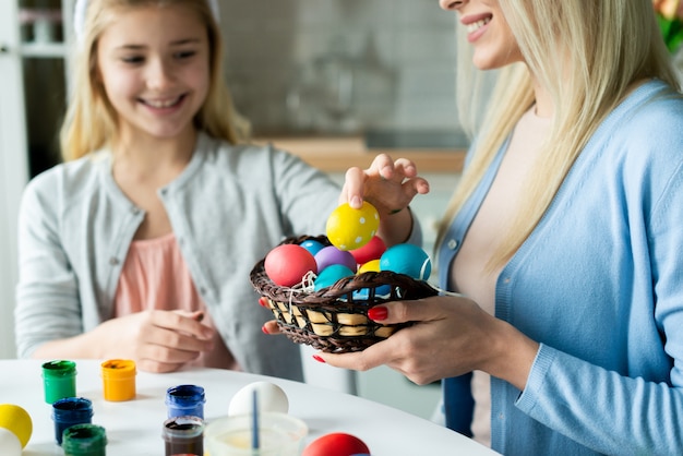 Família feliz, preparando-se para a Páscoa. Filha leva um ovo colorido e sua mãe segurando uma cesta.