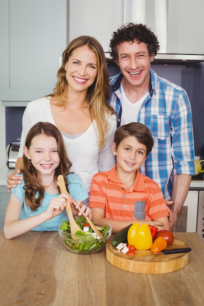 Família feliz, preparando uma salada de legumes