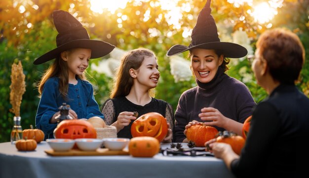 Familia feliz preparándose para Halloween Madre abuela e hijos tallando calabazas