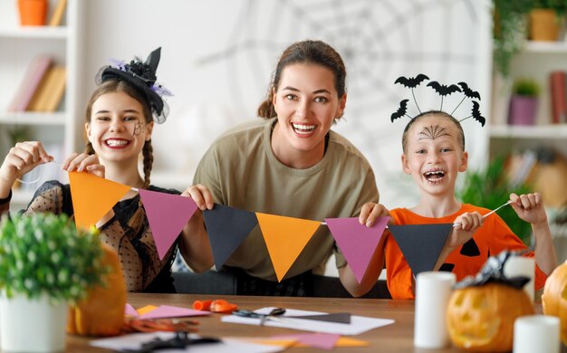 Familia feliz preparándose para Halloween Madre e hijos en trajes de carnaval en casa