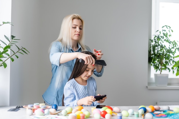 Familia feliz preparándose para Pascua. mamá peinando a su hija.