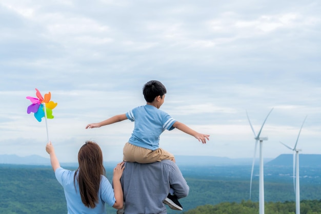 La familia feliz progresiva disfruta de su tiempo en el parque eólico por concepto de energía verde