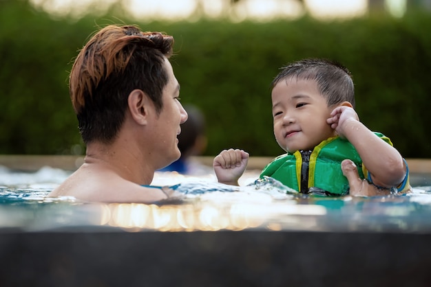 Família feliz que aprecia o tempo da natação na associação em férias de verão.