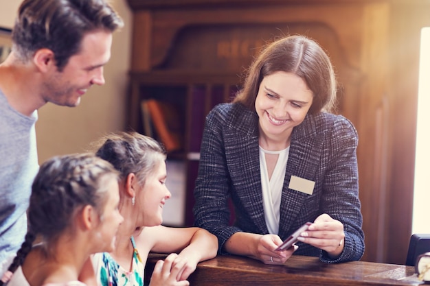 Familia feliz que se registra en el hotel en la recepción